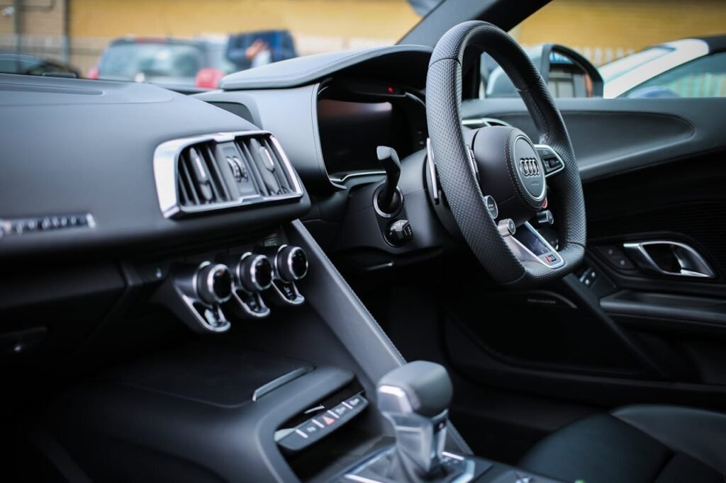 Servicios completos de lavado pulido. Explore the sleek interior of a modern luxury Audi, featuring a detailed view of the steering wheel and dashboard.